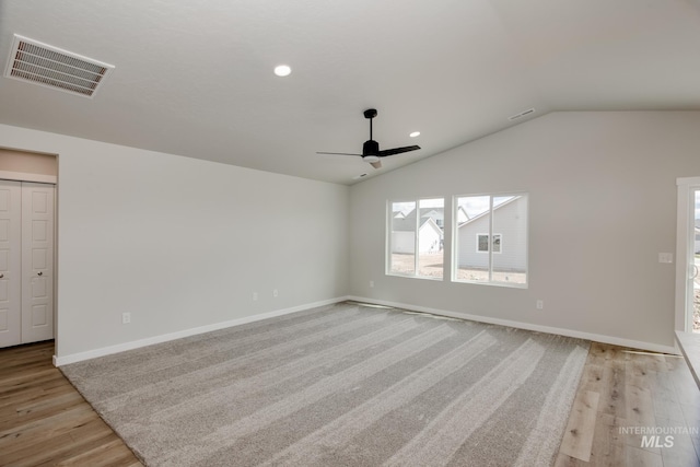 empty room featuring ceiling fan, lofted ceiling, and light wood-type flooring