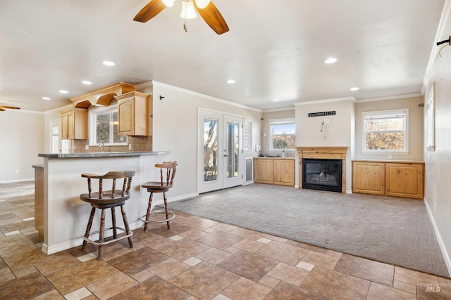 kitchen with light carpet, tasteful backsplash, baseboards, ceiling fan, and ornamental molding