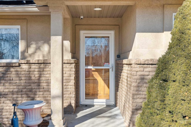 entrance to property featuring brick siding and stucco siding