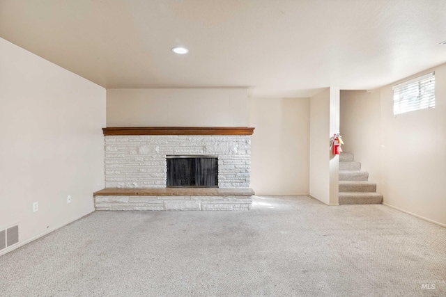 unfurnished living room featuring stairs, a stone fireplace, carpet, and visible vents