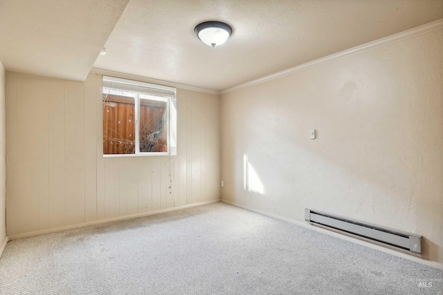 spare room with a baseboard radiator, carpet flooring, crown molding, and baseboards