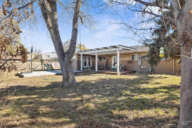 rear view of house featuring a playground, brick siding, a lawn, a pergola, and a patio area