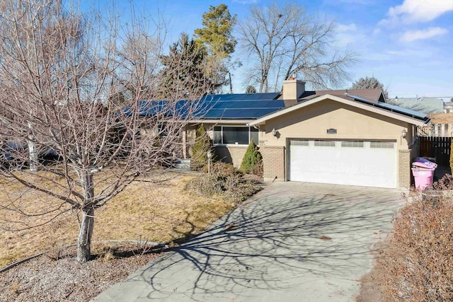 ranch-style home featuring brick siding, a chimney, stucco siding, solar panels, and driveway