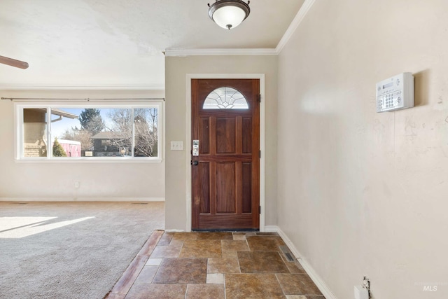 carpeted entrance foyer featuring stone finish flooring, crown molding, and baseboards