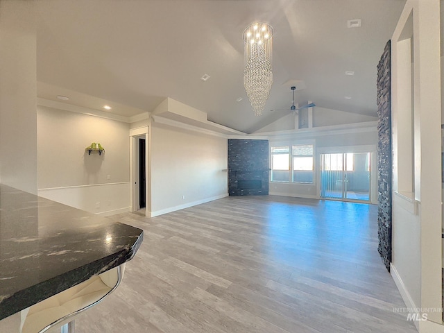 unfurnished living room with ceiling fan with notable chandelier, wood-type flooring, and lofted ceiling