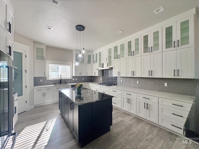 kitchen featuring stainless steel gas cooktop, sink, white cabinets, light hardwood / wood-style floors, and a kitchen island