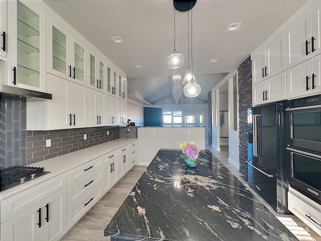 kitchen with tasteful backsplash, light hardwood / wood-style flooring, dark stone counters, white cabinets, and black appliances