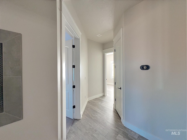 corridor featuring light hardwood / wood-style floors and a textured ceiling