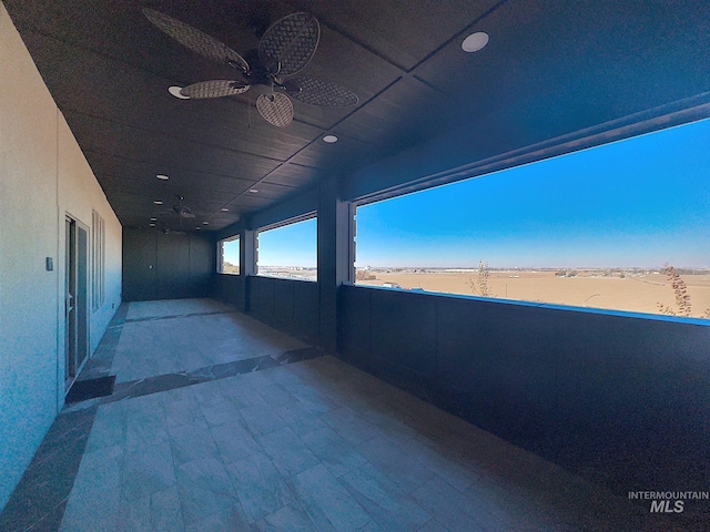 view of patio / terrace with ceiling fan, a balcony, a water view, and a view of the beach