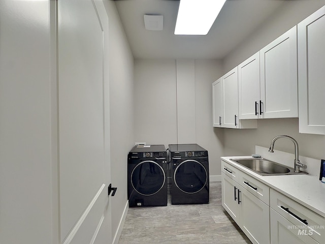 washroom with cabinets, light wood-type flooring, washer and dryer, and sink