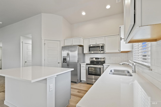 kitchen with tasteful backsplash, a center island, vaulted ceiling, stainless steel appliances, and a sink