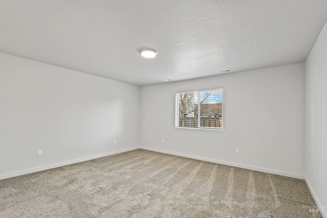 carpeted spare room featuring visible vents, baseboards, and a textured ceiling