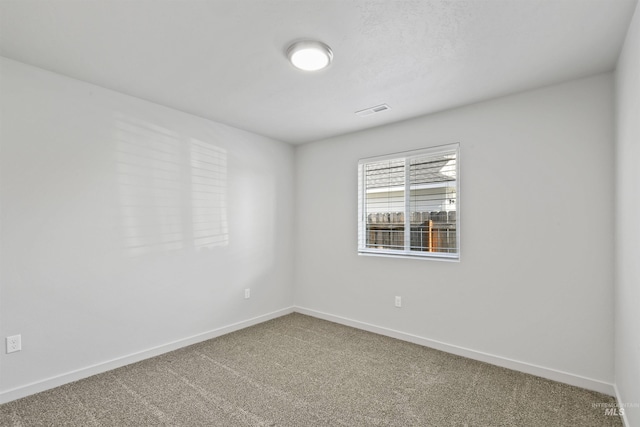 carpeted spare room with visible vents and baseboards