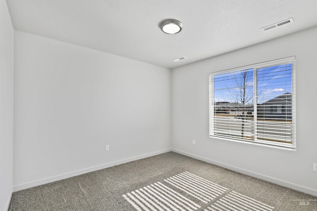 carpeted spare room featuring visible vents and baseboards