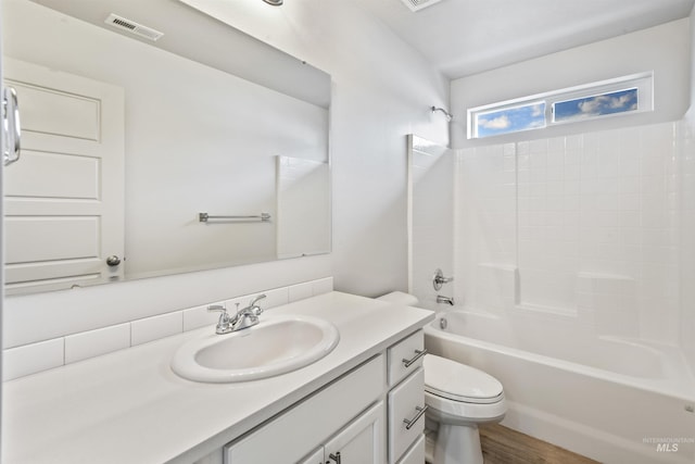 full bath with visible vents, shower / washtub combination, toilet, wood finished floors, and vanity