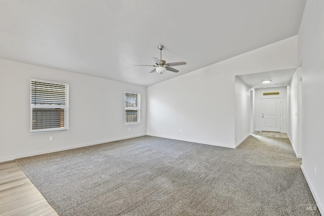 carpeted spare room featuring vaulted ceiling, a ceiling fan, and baseboards