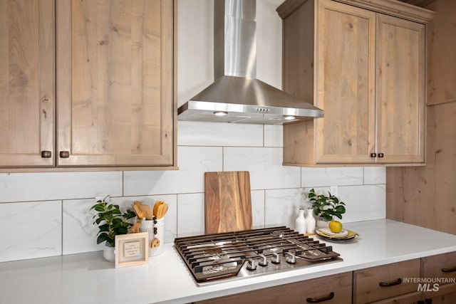 kitchen with stainless steel gas stovetop, decorative backsplash, and wall chimney range hood