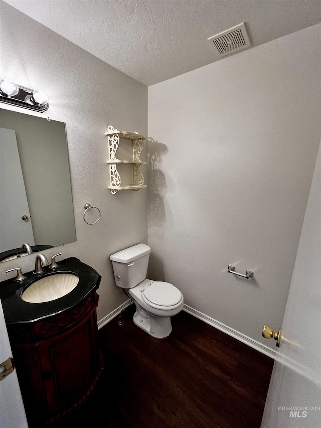 bathroom featuring vanity, hardwood / wood-style floors, a textured ceiling, and toilet