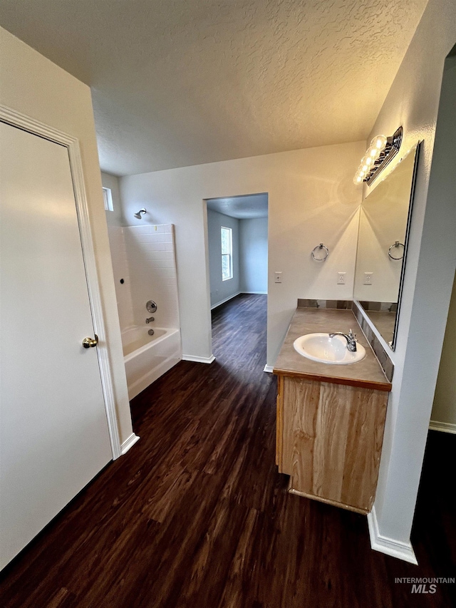 bathroom featuring hardwood / wood-style flooring, vanity, shower / bath combination, and a textured ceiling