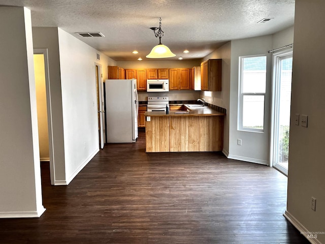 kitchen with dark wood-type flooring, hanging light fixtures, a textured ceiling, kitchen peninsula, and white appliances