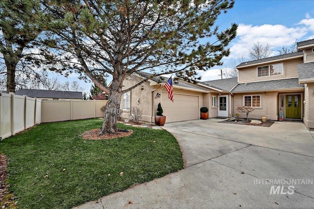 view of front of home with a garage, concrete driveway, a front yard, and fence