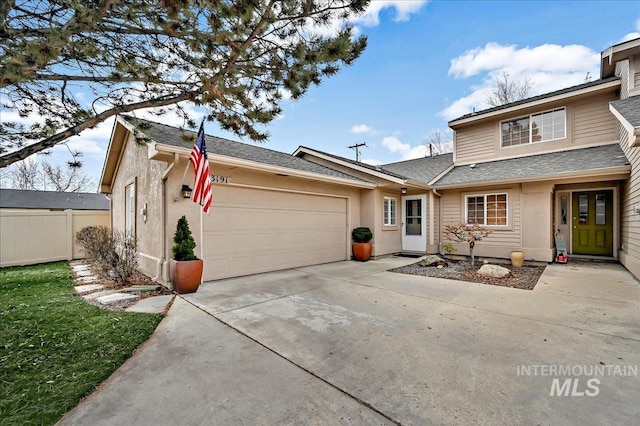 view of front of home featuring roof with shingles, driveway, an attached garage, and fence