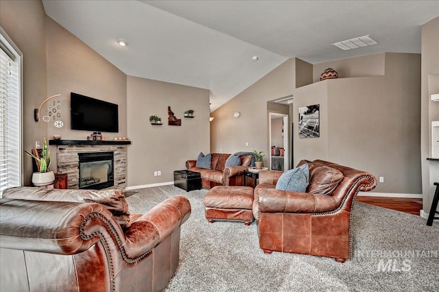 living area with lofted ceiling, a stone fireplace, visible vents, and baseboards