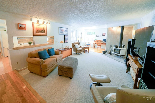 506 Fair Ln, Nampa, ID 83686 - living area with a wood stove, light wood-style flooring, light colored carpet, and a textured ceiling