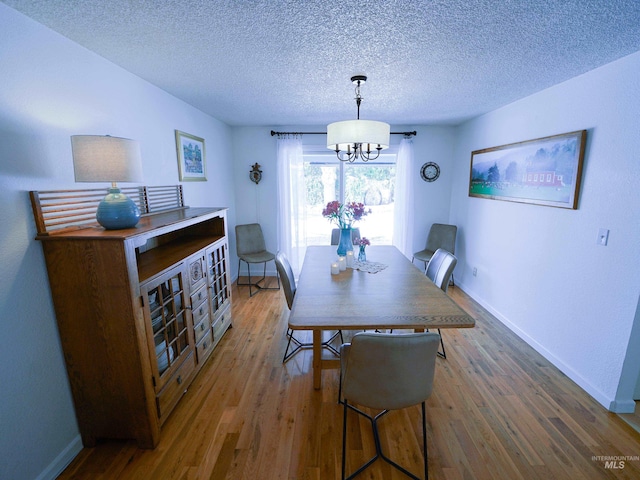 506 Fair Ln, Nampa, ID 83686 - dining room featuring a chandelier, a textured ceiling, baseboards, and wood finished floors