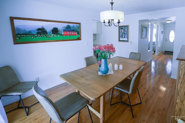 506 Fair Ln, Nampa, ID 83686 - dining area with a notable chandelier, wood finished floors, baseboards, and a textured ceiling