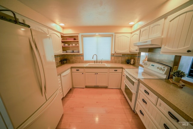506 Fair Ln, Nampa, ID 83686 - kitchen featuring under cabinet range hood, a sink, backsplash, white appliances, and light wood finished floors