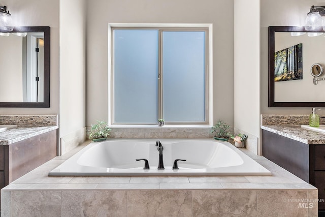 bathroom featuring a relaxing tiled tub and vanity