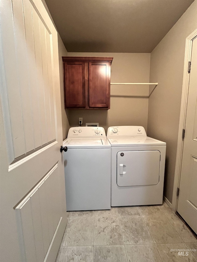 clothes washing area featuring washing machine and clothes dryer and cabinets