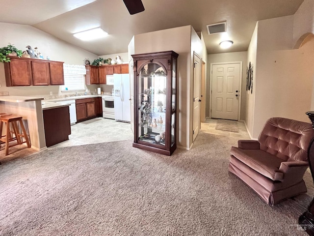 kitchen with kitchen peninsula, a kitchen breakfast bar, white appliances, light colored carpet, and lofted ceiling