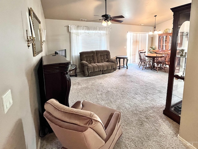 carpeted living room featuring ceiling fan with notable chandelier and vaulted ceiling