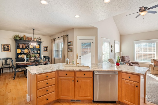 kitchen featuring stainless steel dishwasher, sink, decorative light fixtures, light hardwood / wood-style flooring, and lofted ceiling