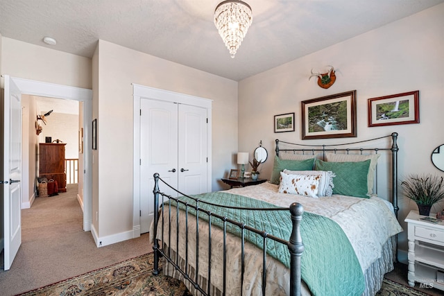 carpeted bedroom with a textured ceiling, a closet, and a notable chandelier