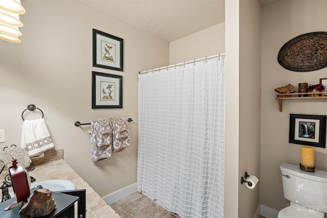 bathroom featuring a textured ceiling, vanity, toilet, and walk in shower