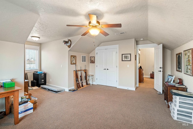 interior space with lofted ceiling, ceiling fan, light colored carpet, and a textured ceiling