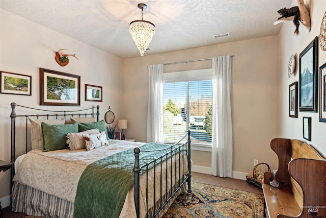 carpeted bedroom with a textured ceiling and an inviting chandelier