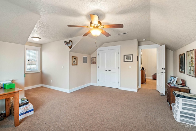 additional living space with a textured ceiling, light colored carpet, vaulted ceiling, and ceiling fan