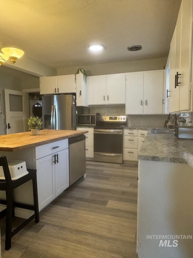 kitchen featuring white cabinets, appliances with stainless steel finishes, dark wood-type flooring, and sink