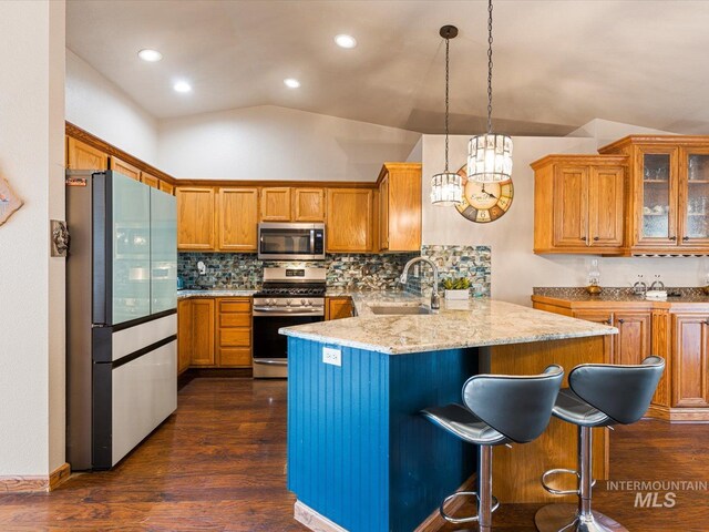 kitchen featuring stainless steel appliances, light stone counters, hanging light fixtures, sink, and dark hardwood / wood-style floors