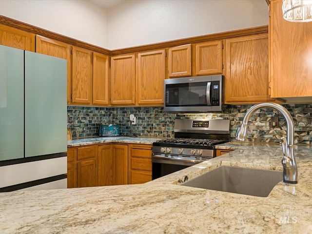 kitchen featuring decorative backsplash, stainless steel appliances, sink, and light stone countertops