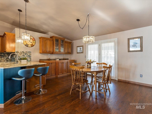 dining space with dark wood-type flooring, sink, an inviting chandelier, and vaulted ceiling