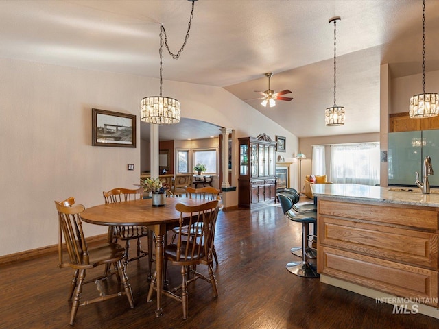 dining area featuring dark hardwood / wood-style flooring, lofted ceiling, ceiling fan, and decorative columns