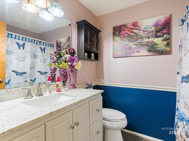 bathroom with toilet, vanity, and curtained shower