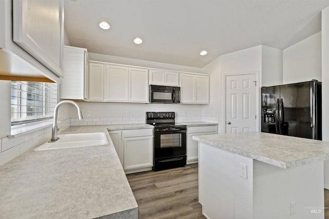 kitchen with black appliances, light wood-style floors, light countertops, and a sink