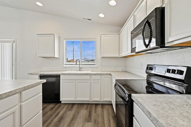 kitchen featuring wood finished floors, a sink, visible vents, vaulted ceiling, and black appliances