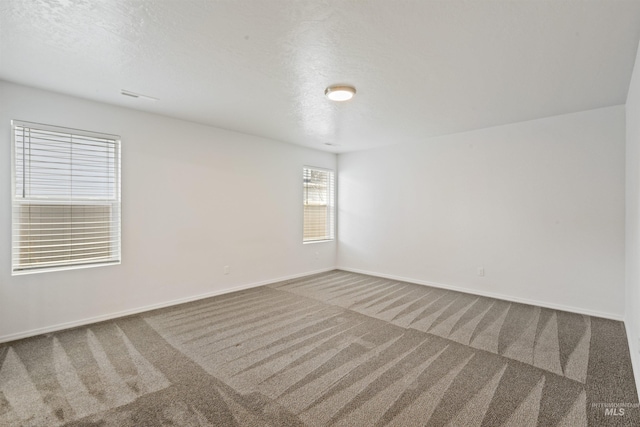 unfurnished room with a textured ceiling, carpet, and baseboards